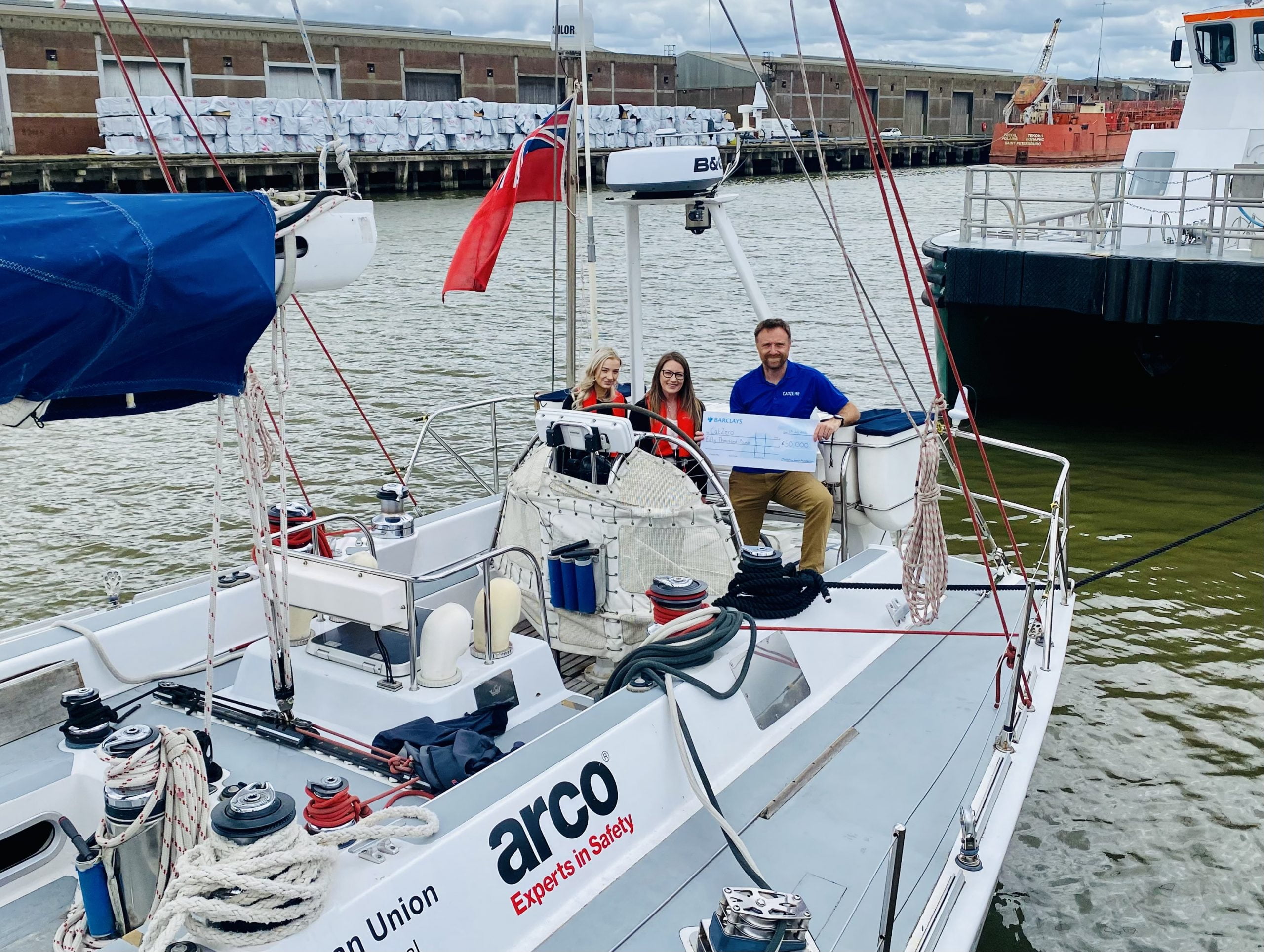 Steph Caley (left) and Michelle Taft (middle) from the Matthew Good Foundation present a £50,000 cheque to Pete Tighe (right) aboard the CatZero yacht.