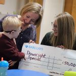 The director of the Matthew Good Foundation hands a cheque for £50,000 to the Manager of Downright Special, a child takes an interest in the cheque