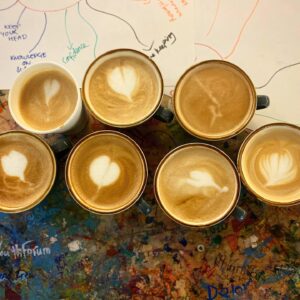 Photograph of Coffee cups from above with patterns in the froth created by practicing students